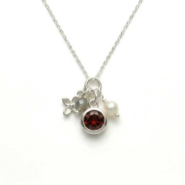 Amali Jules UK sterling silver charm necklace featuring a garnet, labradorite, pearl, and silver flower charm.