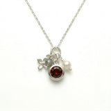 Amali Jules UK sterling silver charm necklace featuring a garnet, labradorite, pearl, and silver flower charm.